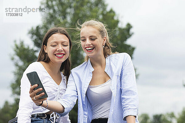 Junge Frau nimmt Selfie durch Handy mit weiblichen Freund