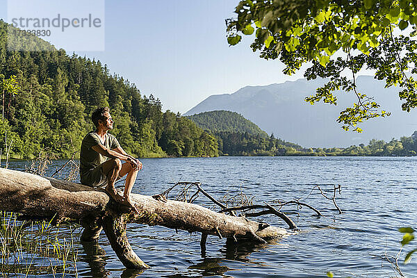 Mann sitzt an einem sonnigen Tag am See
