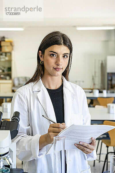 Junge Wissenschaftlerin hält Forschungsdokument im Labor
