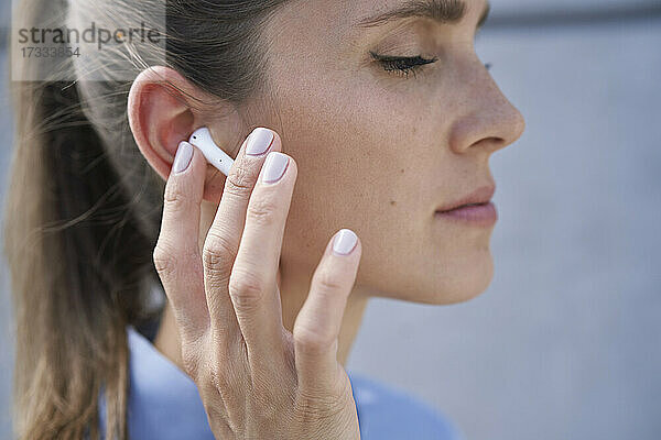 Geschäftsfrau berührt drahtlose In-Ear-Kopfhörer