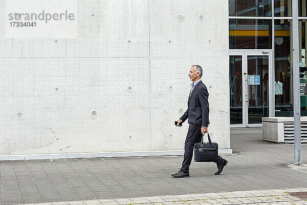 Männlicher Geschäftsmann mit Aktentasche in der Nähe eines Bürogebäudes