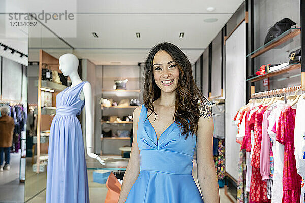 Schöne Frau lächelt in einem blauen Kleid in einer Boutique