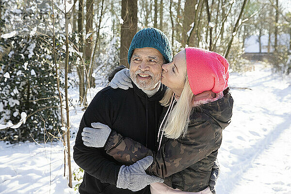 Frau küsst Mann im Wald im Winter