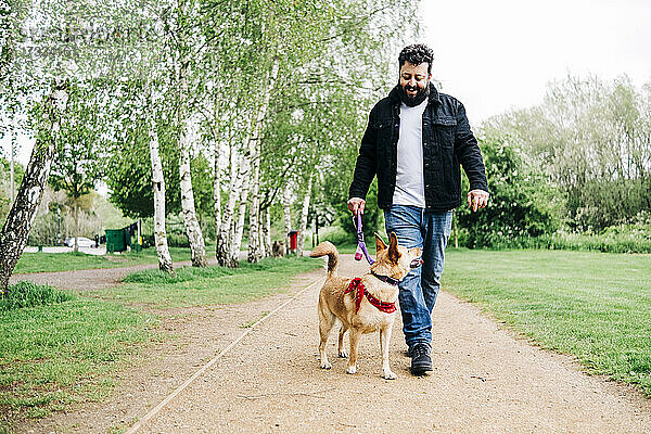 Lächelnder Mann mit Hund auf dem Fußweg im Park