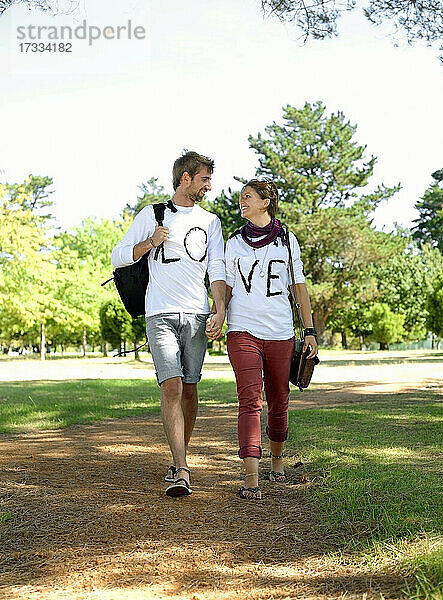 Junges Paar hält sich beim Spaziergang im öffentlichen Park an den Händen