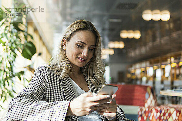 Schöne weibliche Freiberuflerin Text-Messaging beim Sitzen im Café