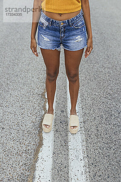Junge Frau in Jeansshorts auf der Straße stehend
