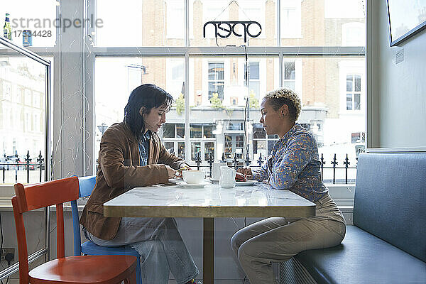 Lesbisches Paar sitzt am Tisch in einem Café am Glasfenster