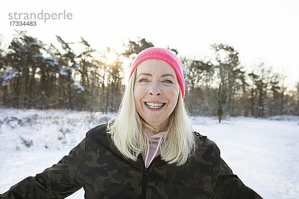 Glückliche blonde Frau mit rosa Strickmütze