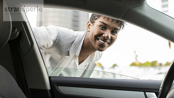Lächelnde weibliche Fachkraft schaut durch ein Autofenster