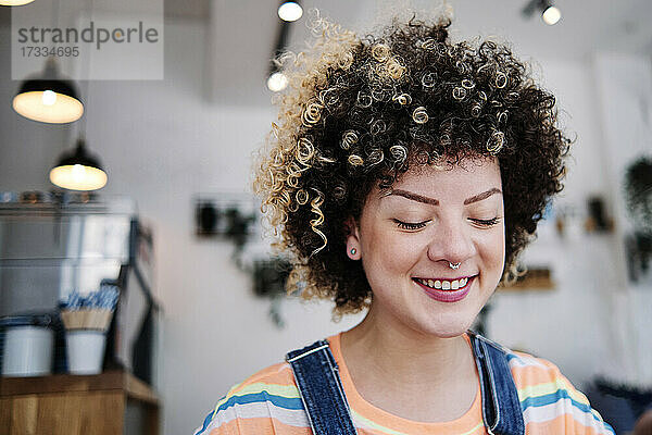 Junge Frau mit geschlossenen Augen lächelt in einem Cafe