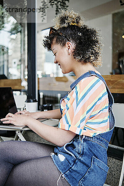 Frau benutzt Laptop in einem Straßencafé