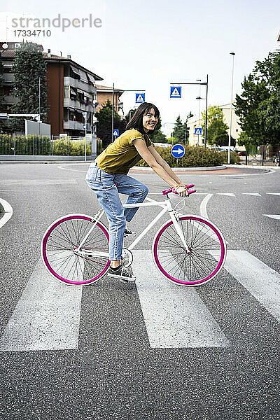 Frau überquert Straße beim Fahrradfahren in der Stadt