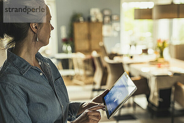 Ältere Frau benutzt digitales Tablet zu Hause