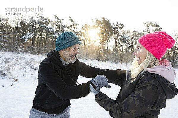 Glückliche Frau spielt mit Mann im Winter