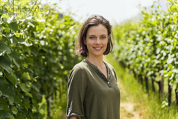 Lächelnde Frau in einem Weinberg an einem sonnigen Tag