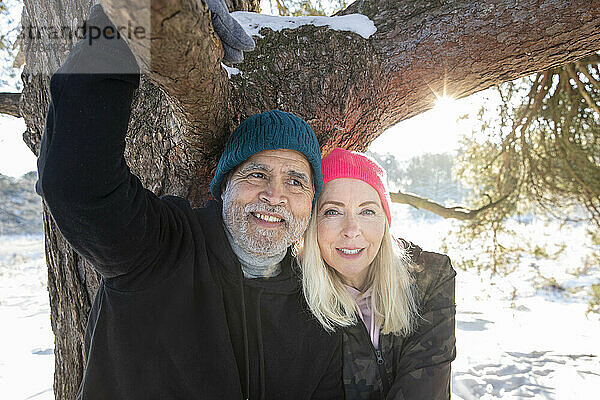 Lächelndes Seniorenpaar unter einem Zweig im Winter