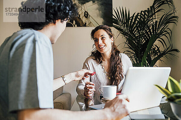 Lächelnde Freundin im Gespräch mit ihrem Freund bei einem Kaffee zu Hause