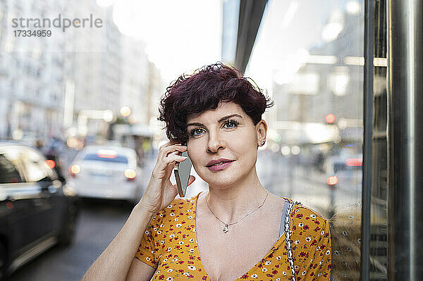 Reife Frau spricht mit Smartphone in der Stadt