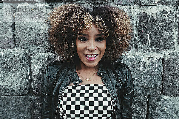 Afro-Frisur Frau lächelnd vor der Wand