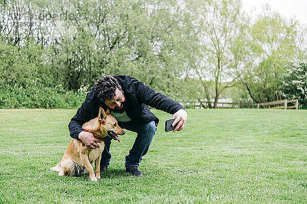 Mann macht Selfie mit Hund im Park