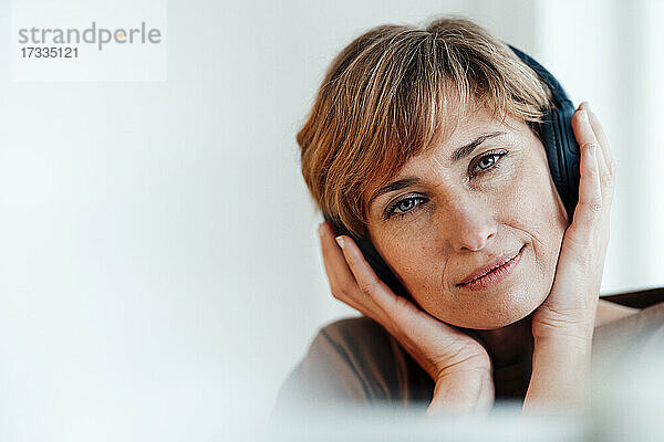 Geschäftsfrau starrt beim Musikhören über Kopfhörer im Büro