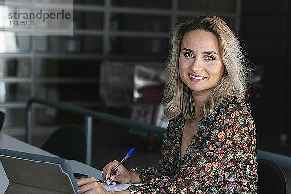 Lächelnde Geschäftsfrau mit digitalem Tablet bei der Arbeit in einem Café