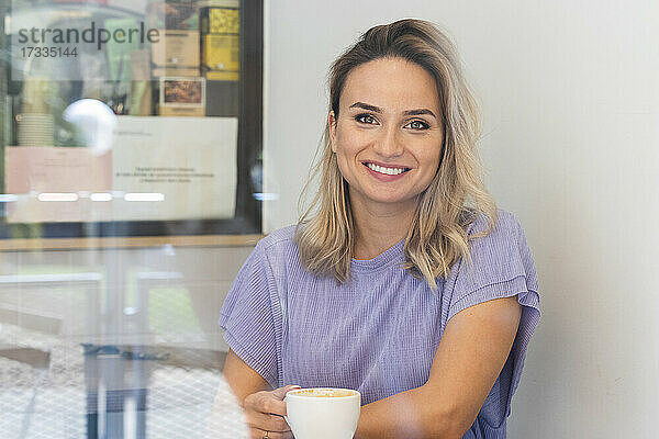 Lächelnde junge Frau bei einem Kaffee im Café