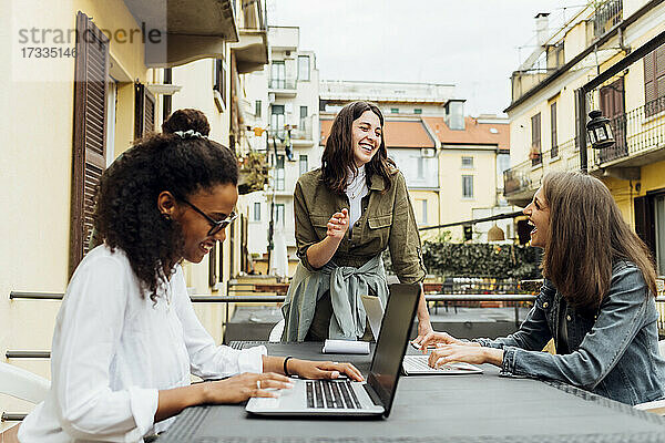 Fröhliche Geschäftsfrauen sitzen mit einem Kollegen auf der Terrasse