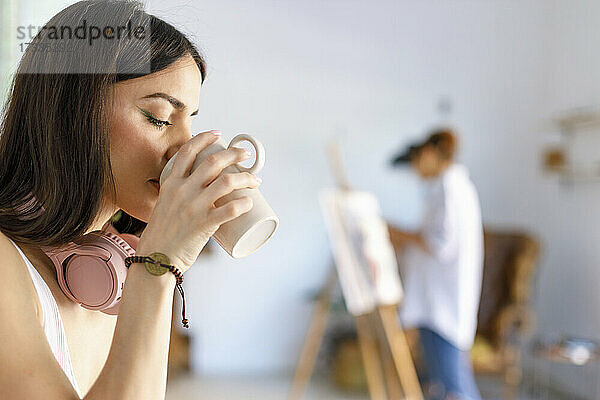 Frau trinkt Kaffee im Atelier eines Künstlers