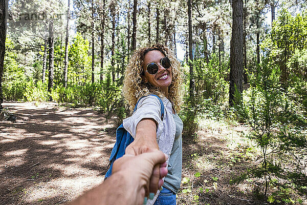 Reifes Paar hält sich an den Händen  während es im Wald unterwegs ist