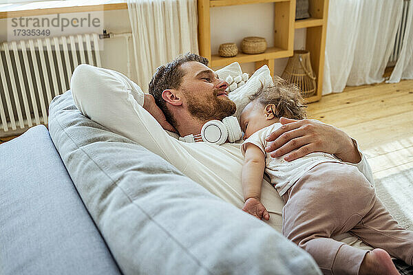 Mann mit Tochter schläft auf dem Sofa zu Hause