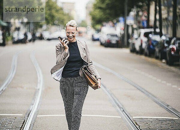 Fröhliche Pendlerin  die in der Straßenbahn mit ihrem Mobiltelefon spricht