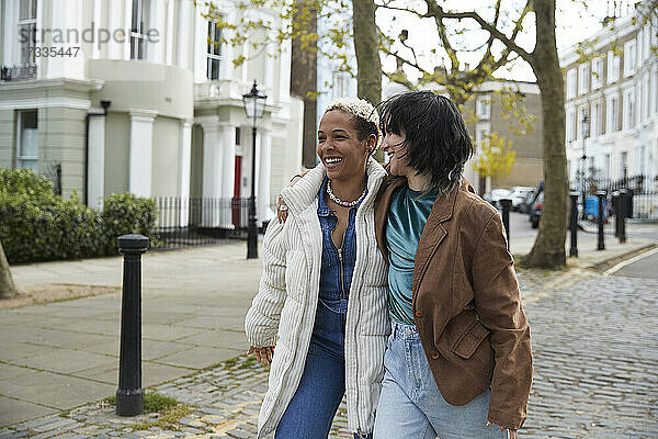 Glückliches lesbisches Paar  das auf dem Gehweg spazieren geht und sich umarmt