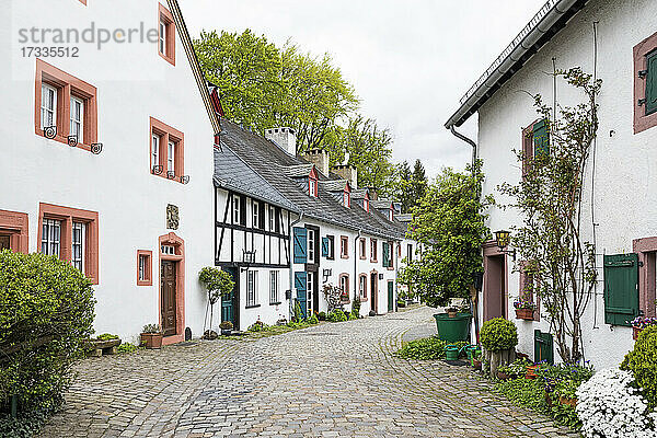 Deutschland  Nordrhein-Westfalen  Kronenburg  Rustikale Häuserzeile entlang einer Kopfsteinpflasterstraße in einem historischen mittelalterlichen Dorf