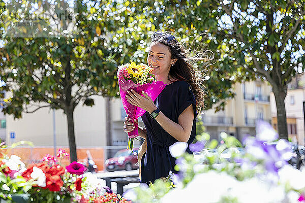 Lächelnde Frau mit Blumenstrauß in einem Blumenladen