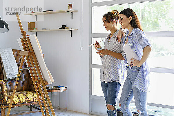 Künstlerinnen betrachten ein Gemälde  während sie zusammen in einem Kunstatelier stehen
