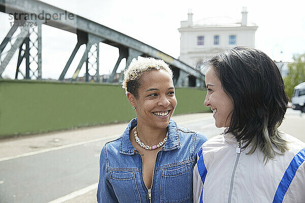 Lesbisches Paar  das sich auf einer Brücke lächelnd ansieht
