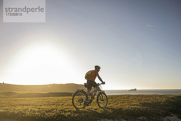 Männlicher Sportler fährt Mountainbike auf einer Wiese