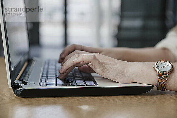 Hände einer Freiberuflerin beim Tippen auf einem Laptop in einem Café