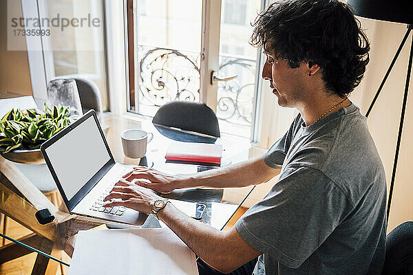 Mann benutzt Laptop bei der Arbeit von zu Hause aus