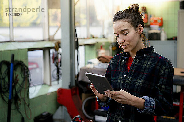 Mechanikerin mit digitalem Tablet in der Werkstatt