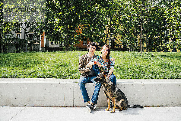 Paar sitzt zusammen mit einem Hund auf einer Bank
