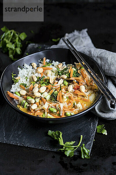 Veganes gelbes Thai-Curry mit Stahlstäbchen auf schwarzem Tisch