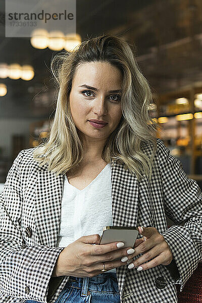 Schöne Geschäftsfrau hält Smartphone beim Sitzen im Café