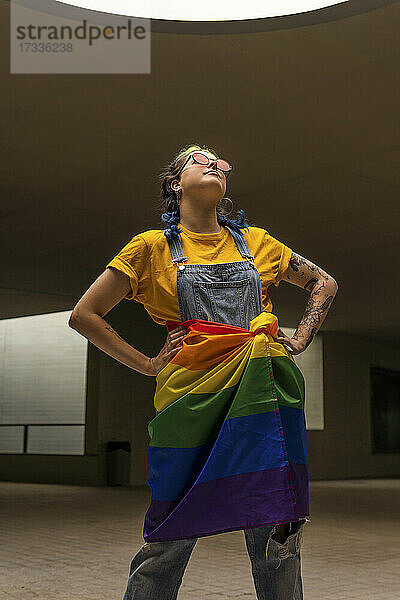 Hipster-Frau stehend mit Regenbogenflagge um die Taille gebunden