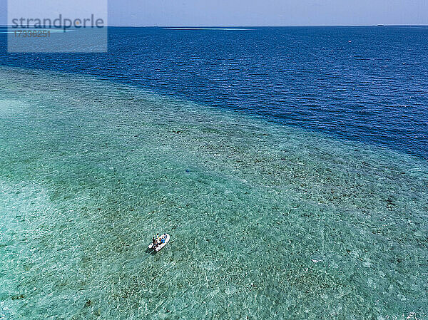 Malediven  Luftaufnahme eines einsamen Motorboots auf dem türkisfarbenen Wasser des Indischen Ozeans im Sommer