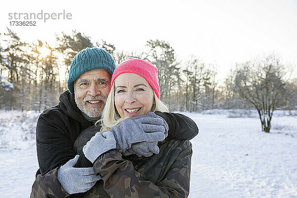 Lächelnder älterer Mann  der im Winter den Arm um eine Frau legt