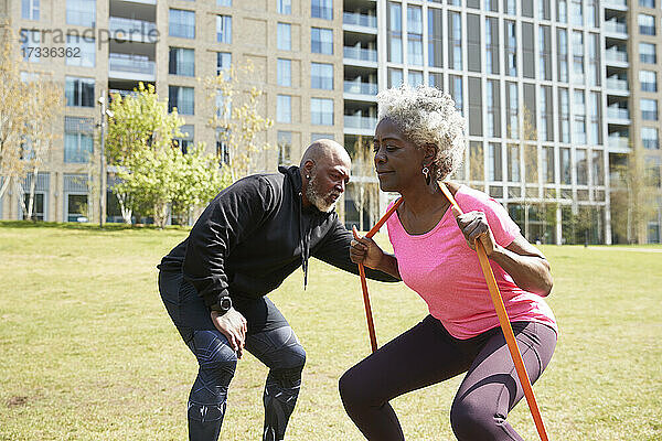 Mann hilft einer älteren Frau beim Training mit einem Widerstandsband im Park