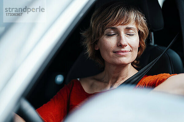 Geschäftsfrau sitzt mit geschlossenen Augen im Auto